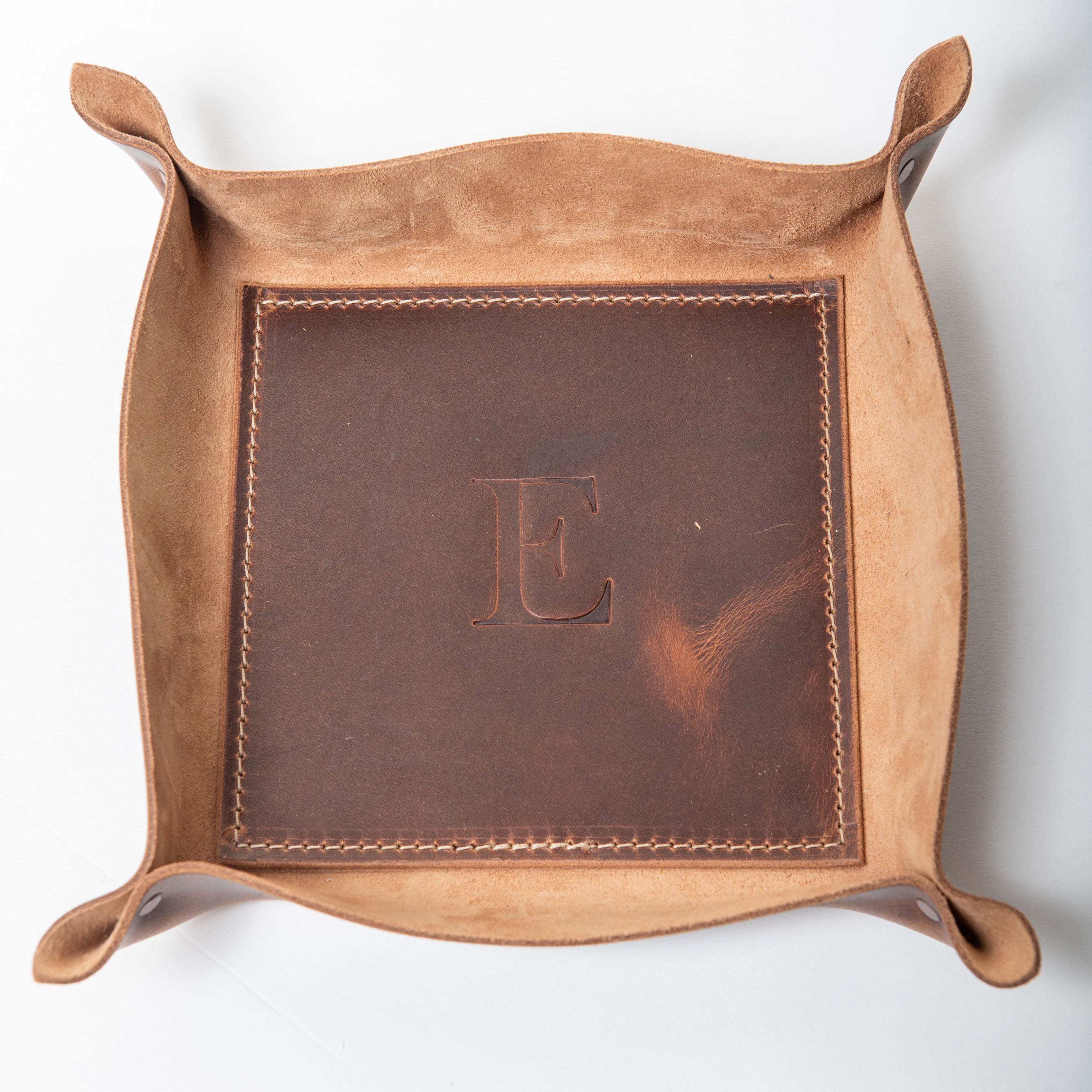 Brown leather tray with a central 'E' embossing on a white background